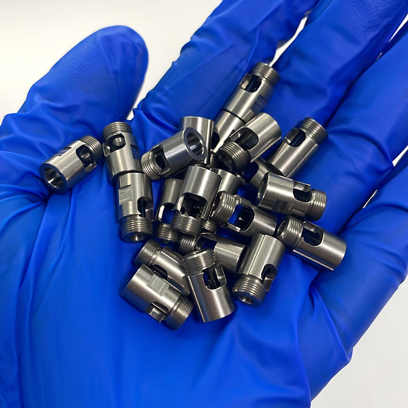 Miniature precision machined metal components shown at hand scale